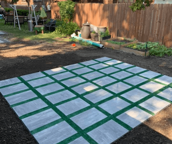 Large square stone patio with artificial turf lined in between each stone