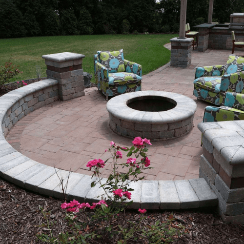 Round patio seating wall, made with grey paving stones encircling a paver fire pit