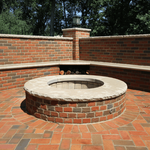 Brick patio seating wall with a brick wall behind it encircling a brick fire pit on top of a brick patio