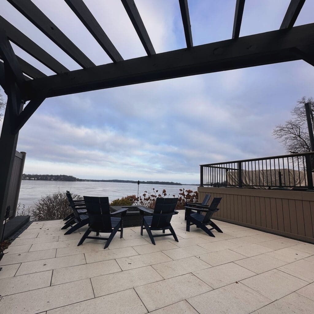 modern patio with lake view and all black pergola overhead