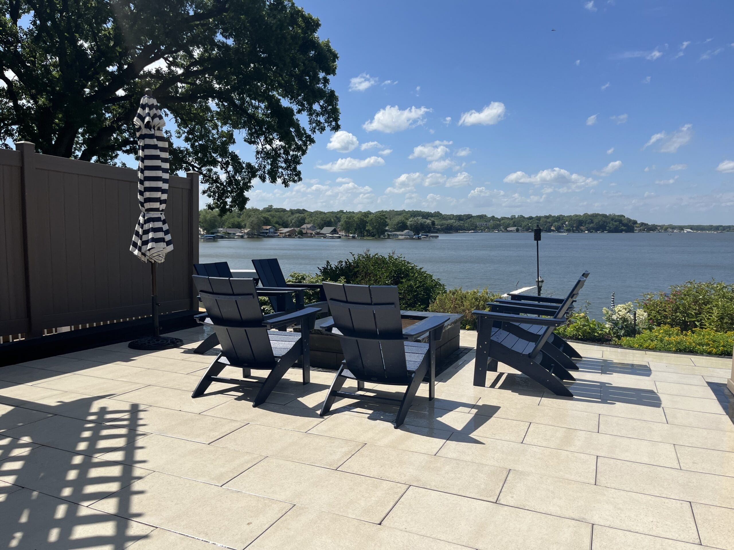 Lakefront Paver Patio with Outdoor Seating Lakefront paver patio with outdoor seating overlooking the water on a sunny day.